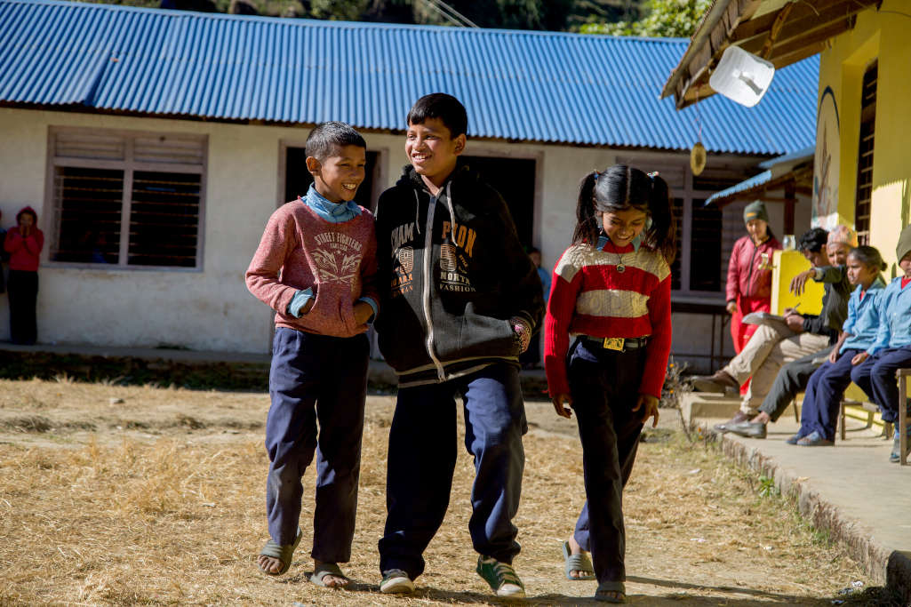 Naresh cammina nel cortile della scuola in mezzo a due amici
