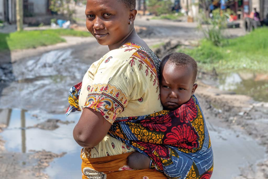 donna con bimbo in fascia sulla schiena