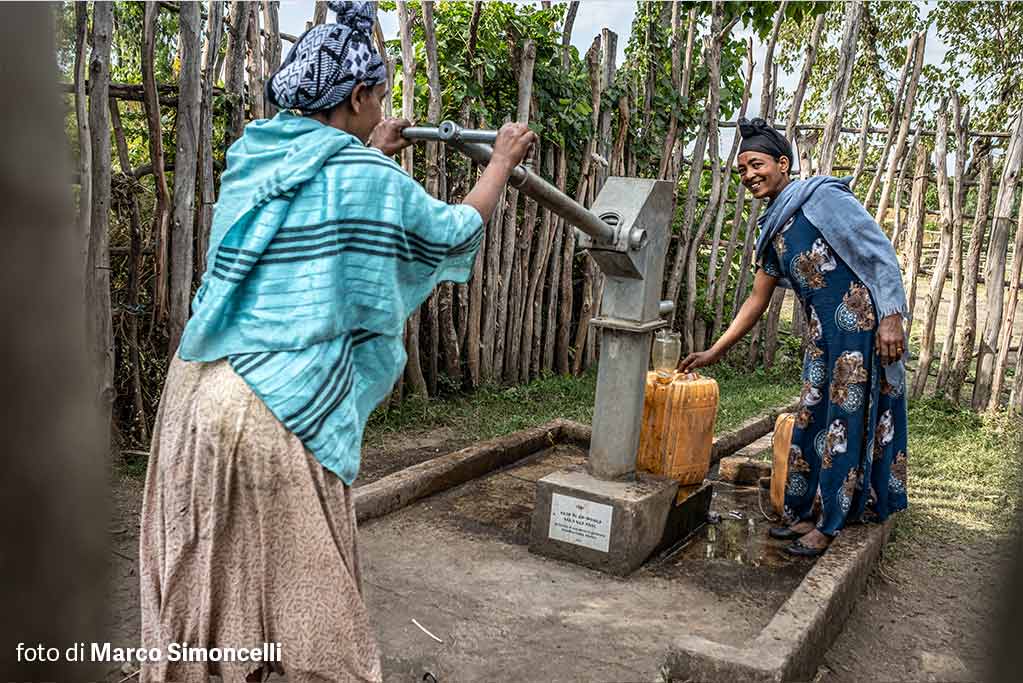 donne caricano la tanica d'acqua al pozzo