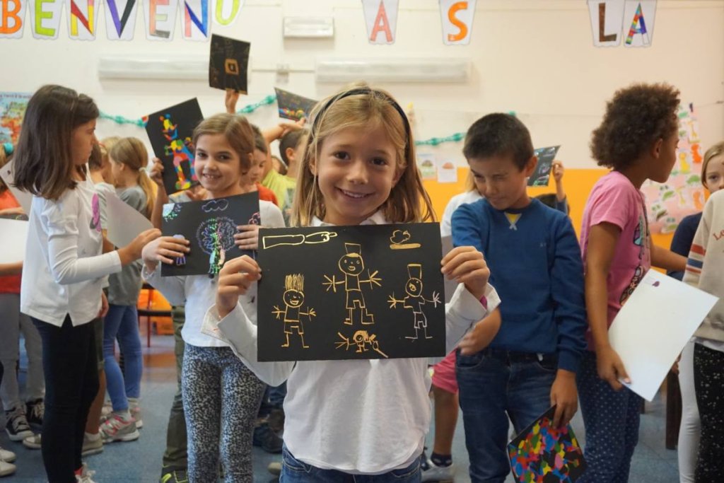 una bambina in classe mostra un lavoretto